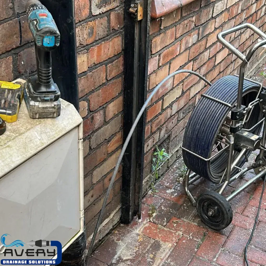 CCTV drain survey camera being inserted into a drain pipe by a professional