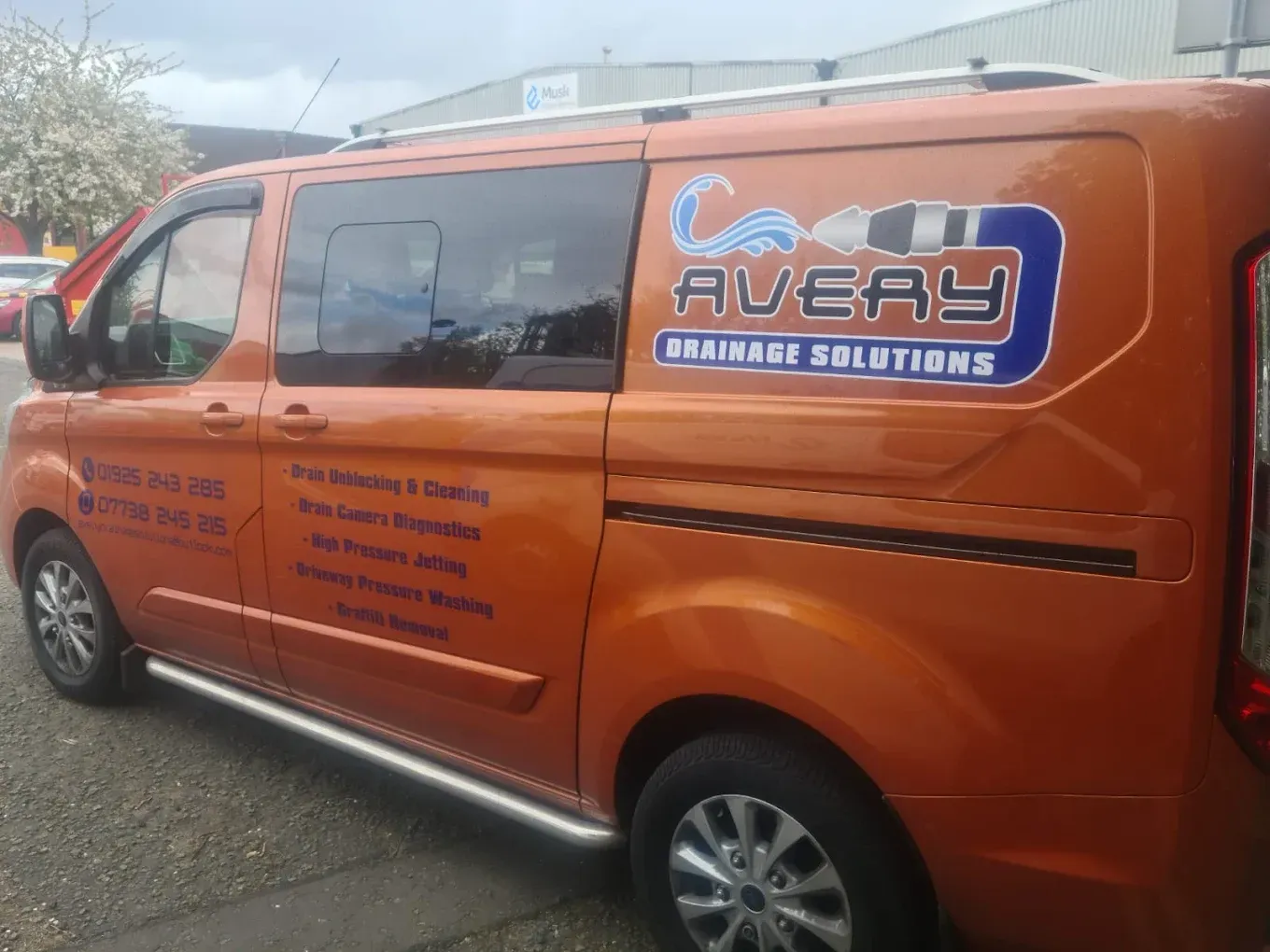 Orange Avery Drainage Solutions van showing logo, phone numbers, and services like drain unblocking, CCTV surveys, and high pressure jetting.